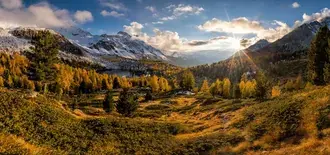Sunlight rising through the clouds in the sky reflects on the trees and snowy mountains 6K wallpaper