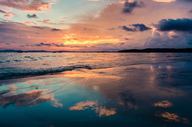 Sonnenaufgangswolken, die sich über das Meer und den Strand spiegeln