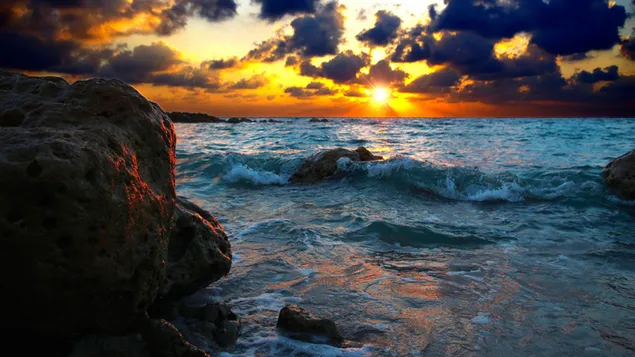 Sonnenuntergang und Wellen, die auf den Felsen brechen