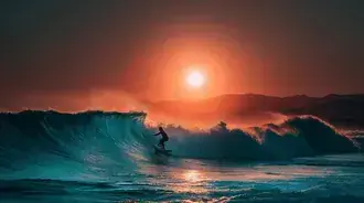 atleta surfista montando una ola gigante en el oceano frente a un pintoresco atardecer. descargar