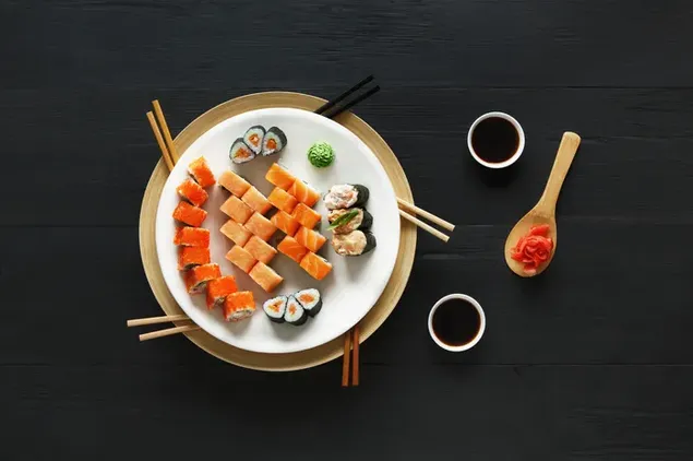 Sushi and sushi rolls in a round plate with soy sauce, ginger, wasabi and chopsticks 