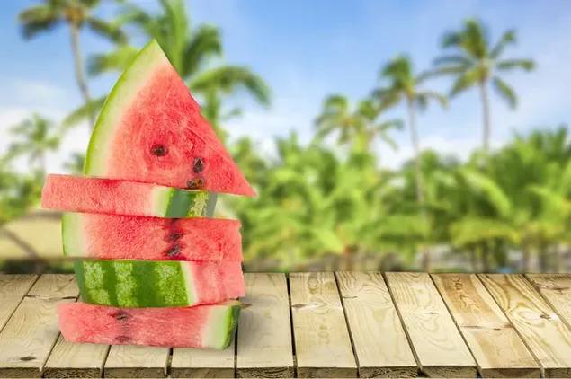 irisan semangka yang manis dan menyegarkan dengan latar belakang pohon palem unduhan