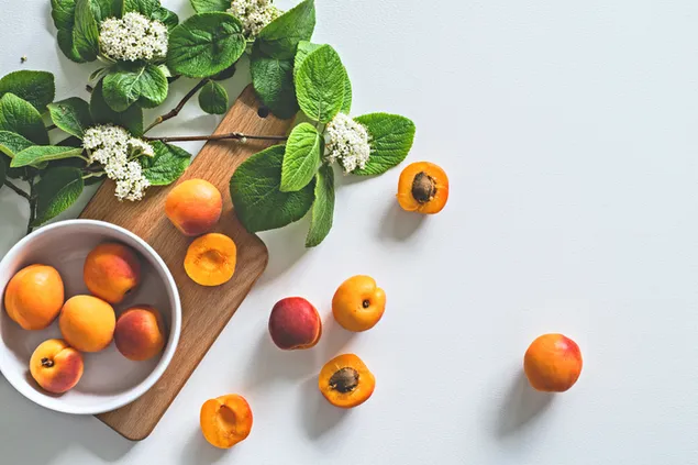 Taustakuva Makea persikka-aprikoosi kulhossa, jossa on puulevy ja valkoinen kukka 4K