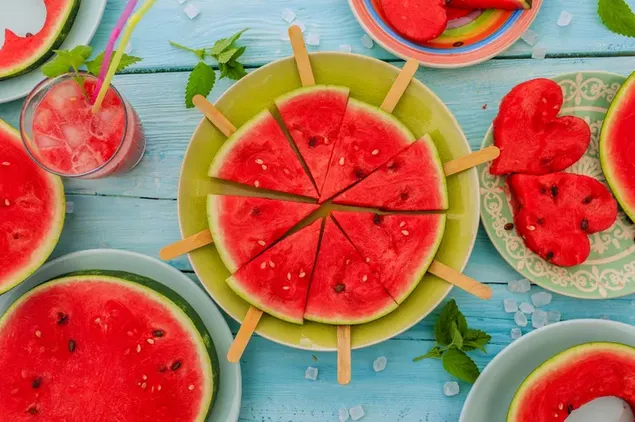 Süße Wassermelonenfrüchte in verschiedenen Formscheiben und ein Glas Wassermelonensaft