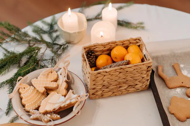 Mesa preparada de una taza de Galletas y una canasta de Naranja con velas