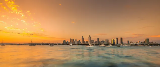 تتشابك مباني المدينة الشاهقة مع السماء والبحر ، فتضرب أشعة الشمس ذات اللون الأصفر 2K خلفية