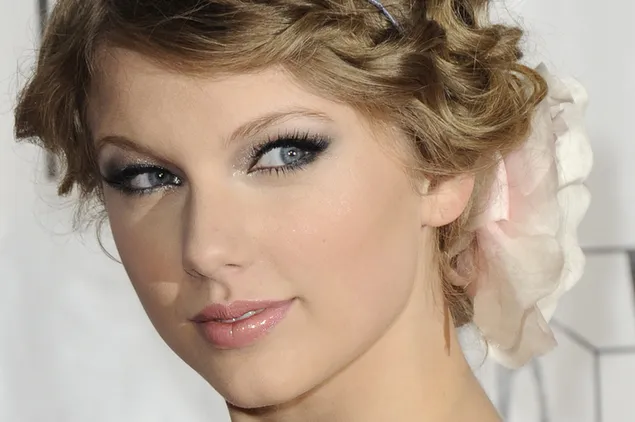 Taylor Swift mit zurückgebundenen blonden Locken, die sie mit blauen Augen ansah