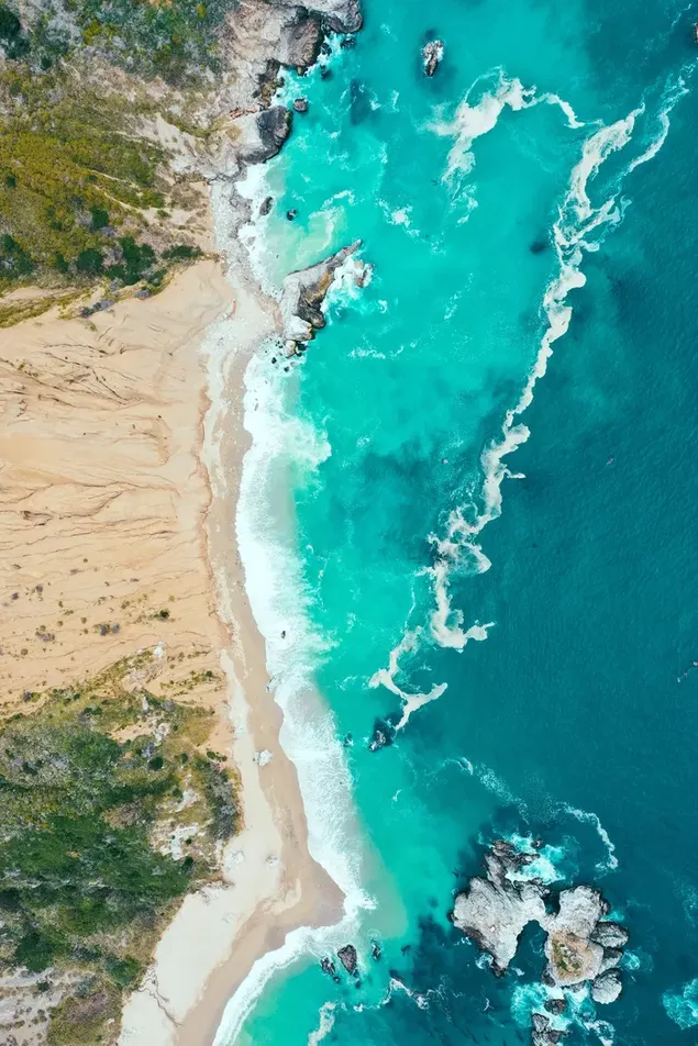 Der Schaum der Wellen, die vom Meerwasser gebildet werden und sich bis zum Sand am Strand erstrecken, schafft ein wunderbares Bild.