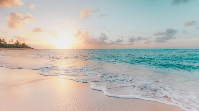 La imagen del sol saliendo más allá del mar en tiempo nublado reflejada en la playa