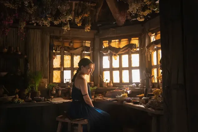 Der Herr der Ringe: Die Ringe der Macht-Schauspielerin in einem blauen Kleid mit geflochtenen Haaren posiert vor dem Fenster im Zimmer 2K Hintergrundbild