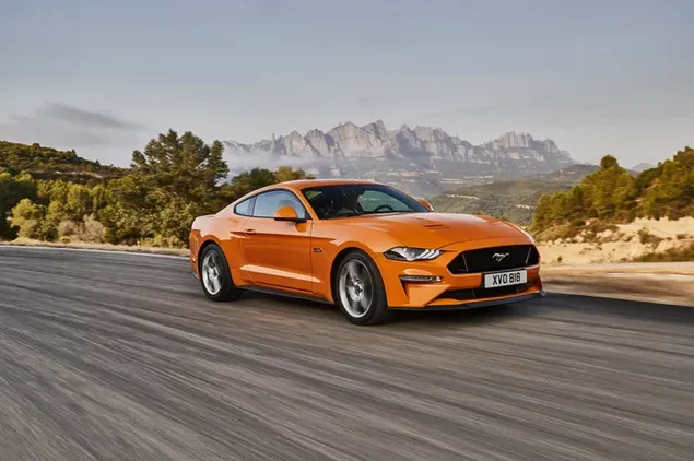 De oranje Ford Mustang GT, een wonder van design dat snel beweegt in de open lucht 4K achtergrond