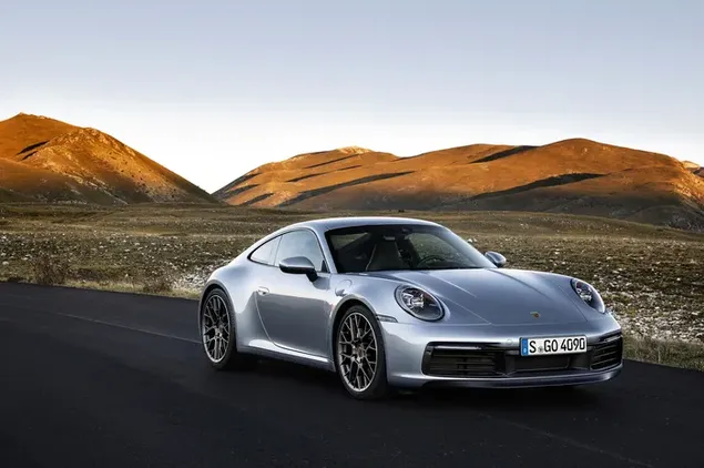 The Porsche 911 Carrera 4S, with its silver-coloured, steel rims, cruising along the road at the edge of the sun-drenched mountains