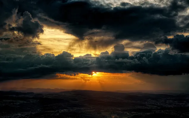 The rising sun reflects on the huge dark clouds above the town HD wallpaper  download