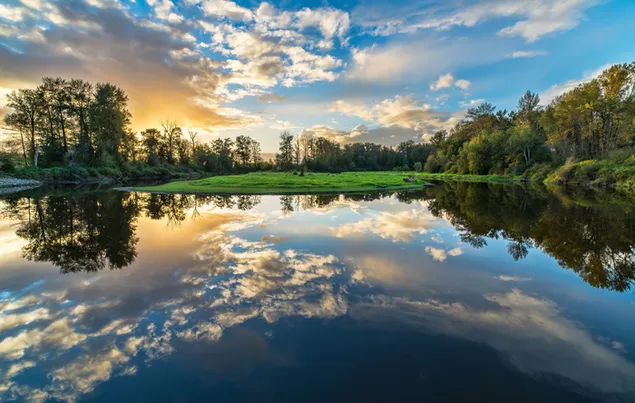 Die Sonne geht nach den schwarzen und weißen Wolken auf und die Reflexion der Bäume und grünen Felder auf dem Wasser 4K Hintergrundbild