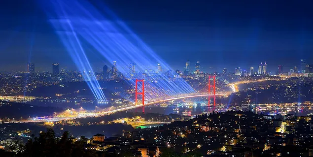 The view of the sea, buildings and Istanbul Bridge decorated with lights in the dark of Istanbul
