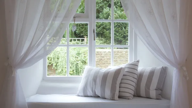 Tre grå- och vitrandiga kuddar och soffdesign vid det klara glasfönstret 4K bakgrund