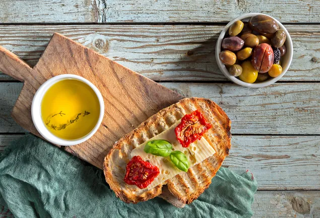 Top de pan tostado con queso, guarnición de aceitunas encurtidas y una taza de té 4K fondo de pantalla