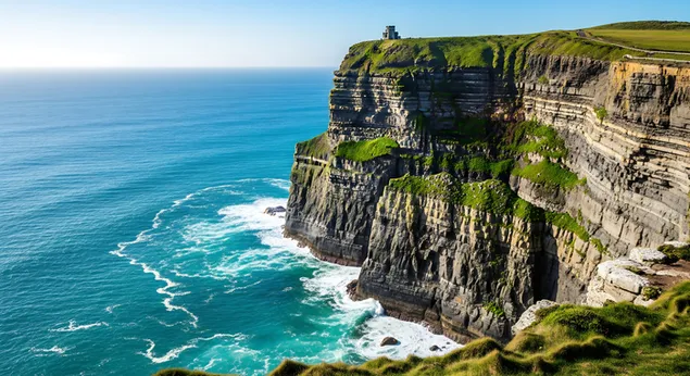 visoke zelene litice dramaticno se uzdizu iznad tirkiznog okeana, gdje se valovi razbijaju o neravnu obalu pod vedrim plavim nebom preuzmi