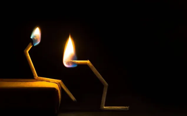 Two burning matchsticks on black background