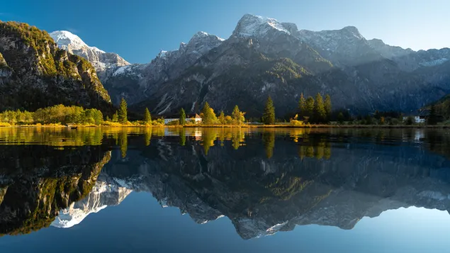 Zwei-Frame-Ansicht eines Quadrats, das durch die Reflexion schneebedeckter Hügel und grüner Wälder im Wasser gebildet wird 2K Hintergrundbild
