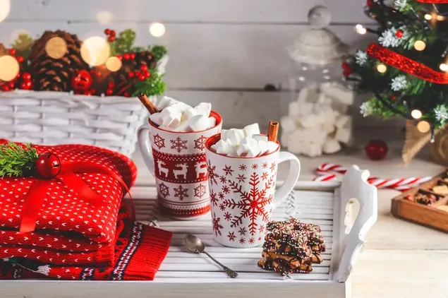 Dua cangkir marshmallow cokelat panas di atasnya dan kue kering di sampingnya dengan latar belakang dekorasi Natal unduhan