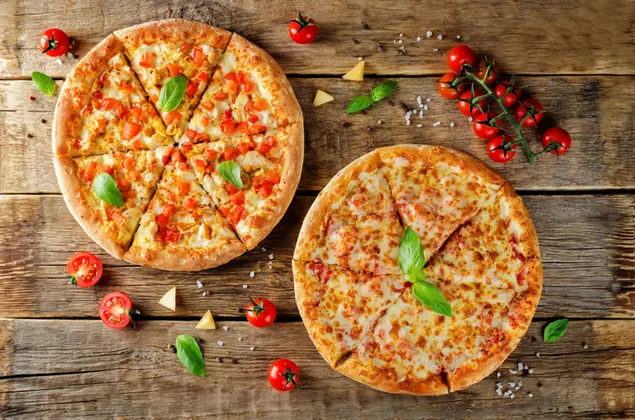 Dua pizza tomat dan keju utuh di meja kayu