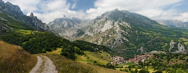 Uitzicht op dorpshuizen met bergen en heuvels bij bewolkt weer tussen natuurlijke groene kleuren