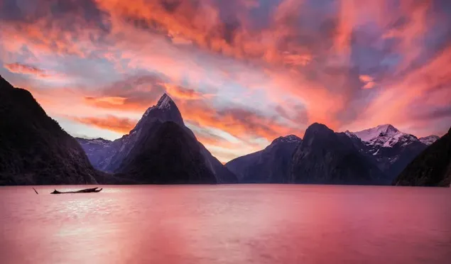 Un pequeño bote en un lago de montaña con una vista naranja de la puesta de sol