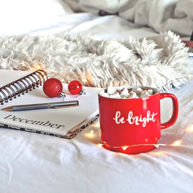 Una taza roja de chocolate caliente con malvavisco para calentar las vacaciones de Navidad