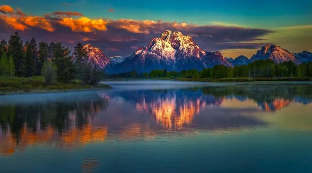 Vista d'arbres, muntanyes nevades i núvols reflectits al llac 4K fons de pantalla