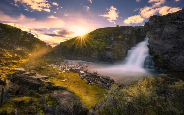 Wasserfall und Sonnenaufgang, die durch die Hügel fließen 2K Hintergrundbild