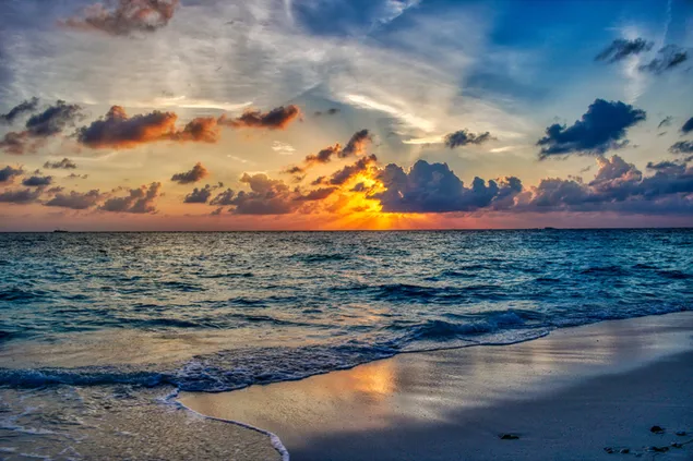 ombak menerjang pantai saat matahari terbenam