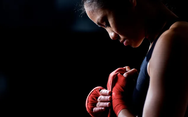 Woman preparing for kickboxing training on black background