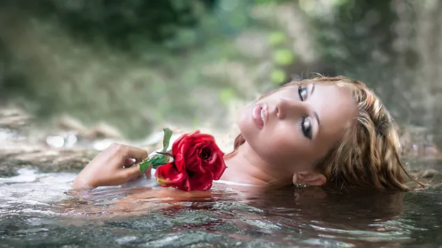 水に横たわっている赤いバラの女性