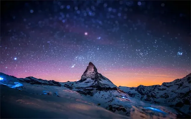 Wunderbarer Blick auf die Sterne und strahlender Blick auf die schneebedeckten Berge in der Abenddämmerung