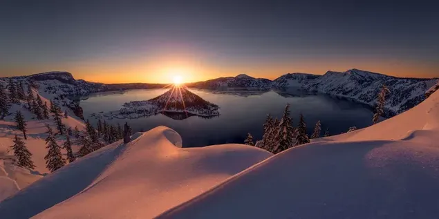 雪に覆われた木々 と雪に覆われた丘の背後にある湖の水の上に昇る太陽