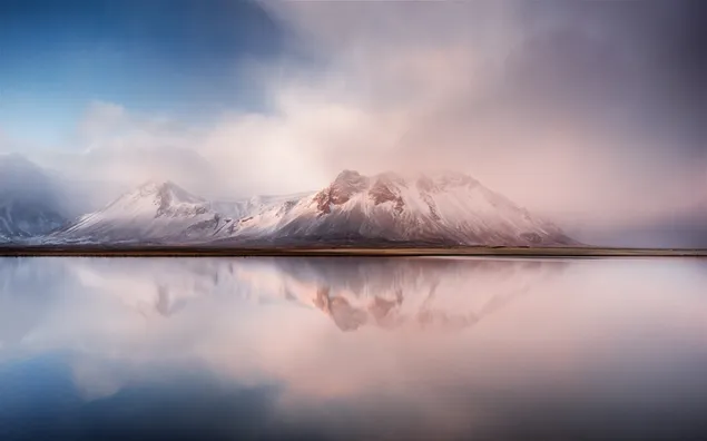 雪に覆われた山の池の反射に沈む雲と夕日