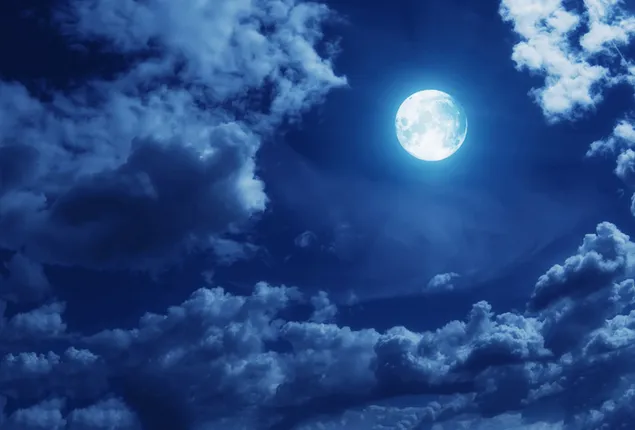 夜の曇り空を照らす満月の画像