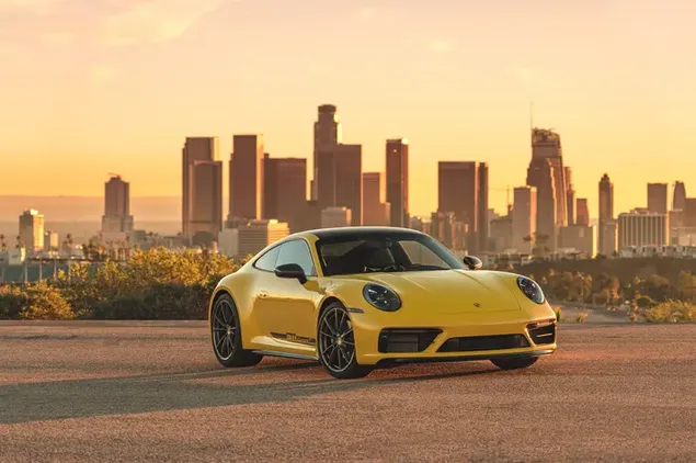 Yellow Porsche 911 parked on asphalt road between city buildings download