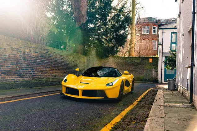 Mobil sport kuning Ferrari diparkir di jalan aspal di antara gedung-gedung dan pepohonan unduhan