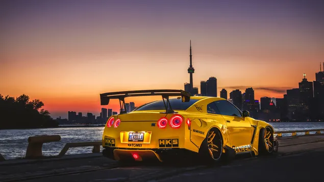 Coche deportivo amarillo Nissan en paisaje urbano nocturno 4K fondo de pantalla