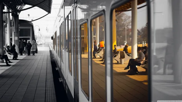 駅で待っている人々の白黒写真と電車の中でカラフルな反射