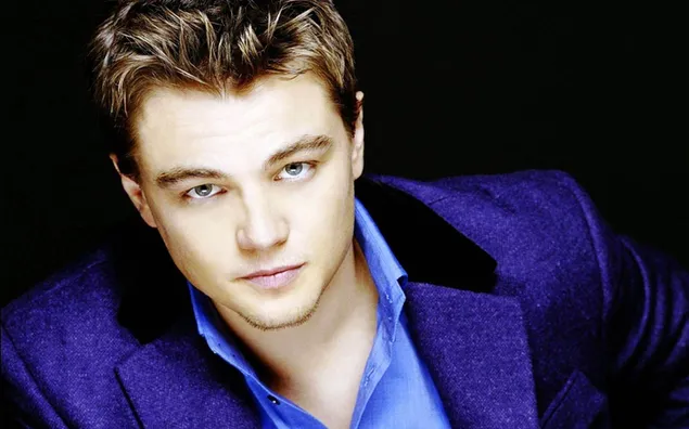Leonardo Dicaprio muda dengan baju biru dan jaket biru, latar belakang hitam 2K kertas dinding