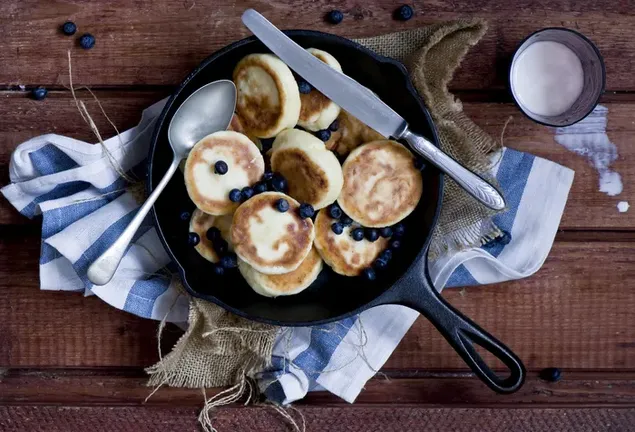 delicieuses crepes aux myrtilles dans une casserole et un verre de lait renverse sur une table en bois telechargement