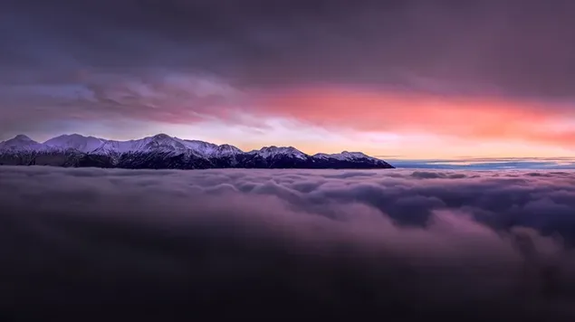 真っ赤な雲に伸びる霧の中にある雪に覆われた山頂